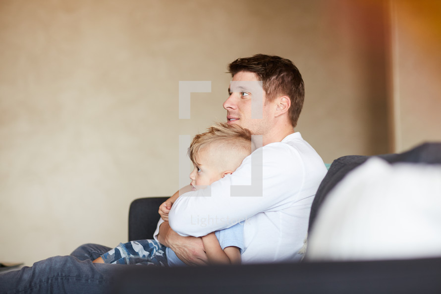a father hugging his son on the couch 