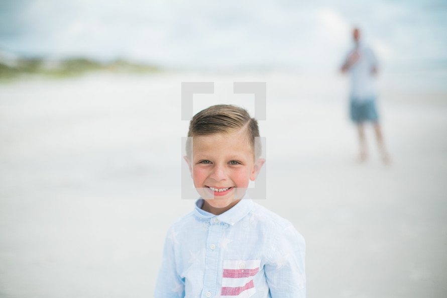 smiling boy standing on a beach 