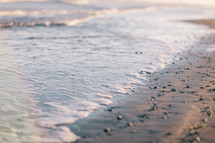 tide washing onto a shore and seashells 