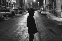 woman standing in the middle of a street at night 