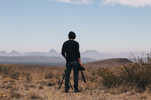 a man holding a camera looking out at mountains 