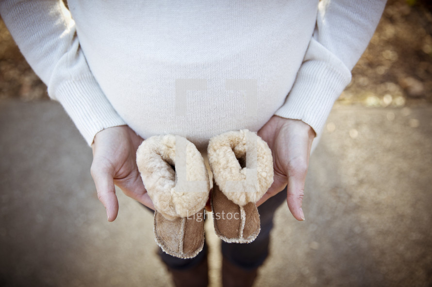 pregnant mother holding empty baby shoes