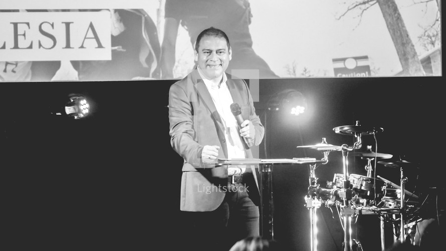 a minister holding a microphone on stage during a worship service 