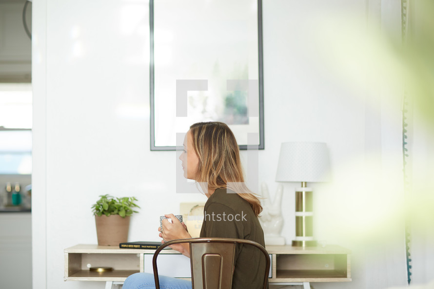 a woman with a coffee mug sitting at a desk 