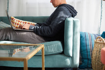 a man sitting on a couch with his laptop in his lap 