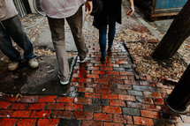 pedestrians walking on a red brick sidewalk 