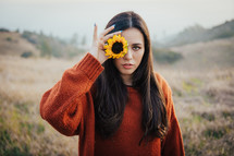 a woman holding a yellow sunflower 