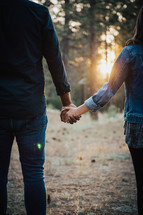 a couple holding hands in a forest 
