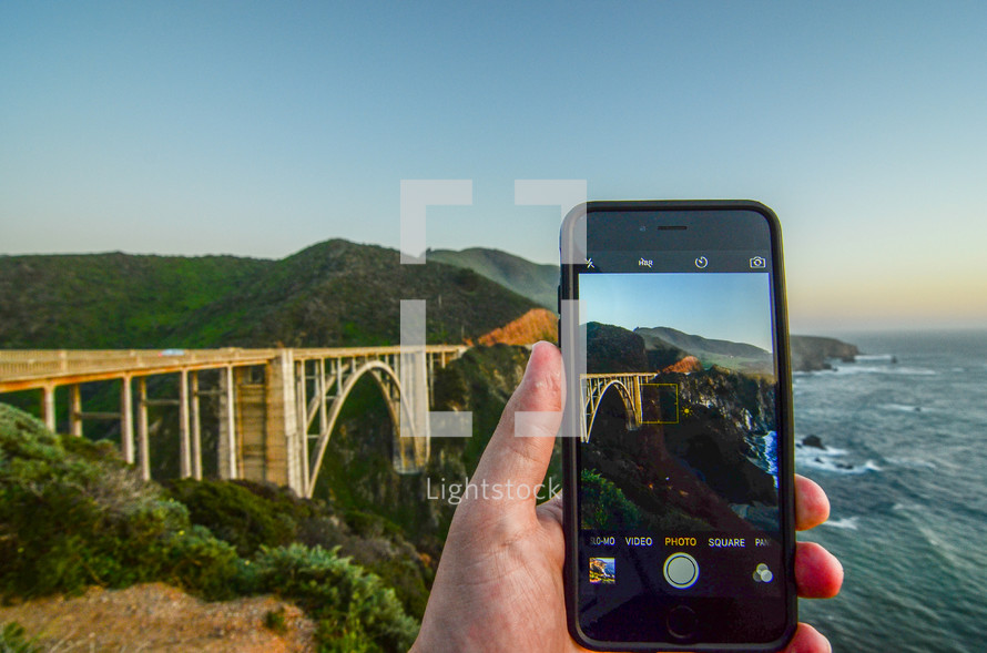 taking a picture of a bridge along a shoreline 