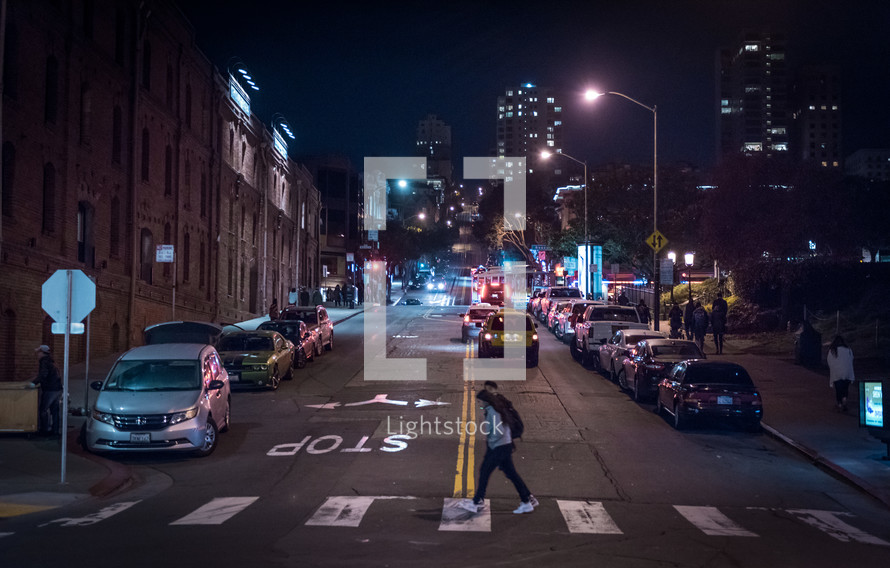 man crossing a crosswalk at night 