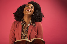 smiling woman reading a Bible and looking up to God 