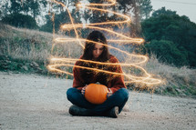 a woman holding an orange pumpkin 