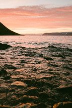 choppy sea water along a shore at sunset 