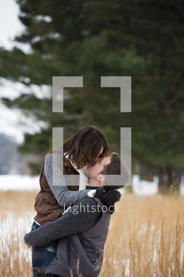 couple kissing in a field 