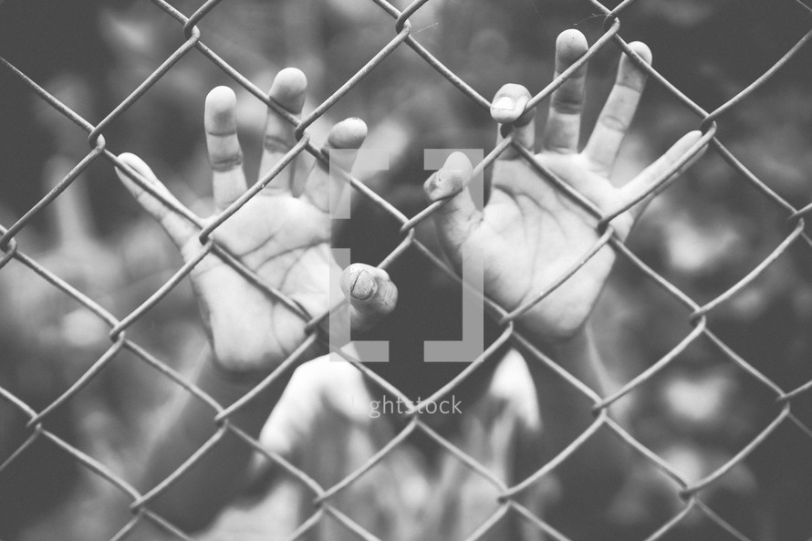 hands on a chain link fence 