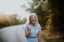 laughing young woman standing in the middle of a rural road 