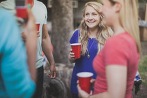 friends holding red cups and talking at a cookout 