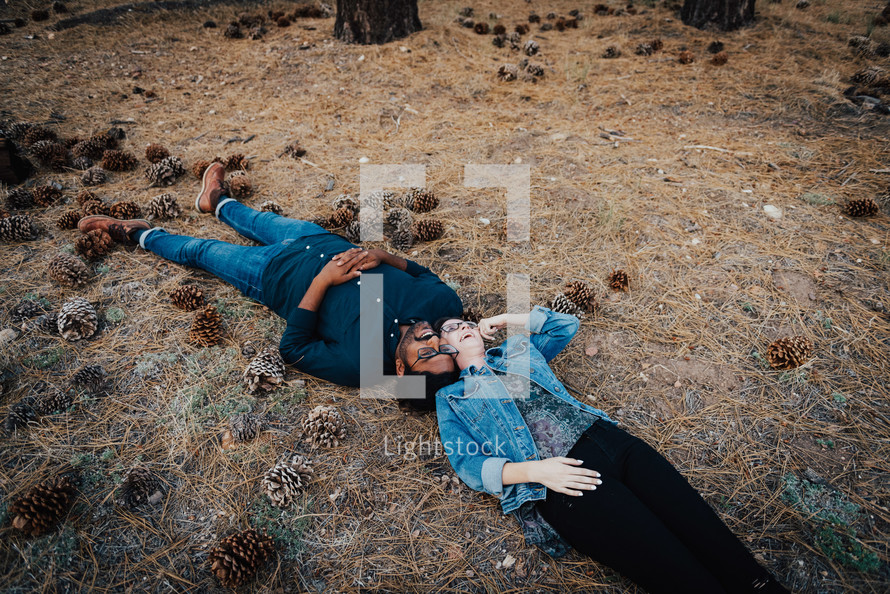 a couple lying together on the forest floor 