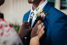 a woman adjusting a man's boutonniere