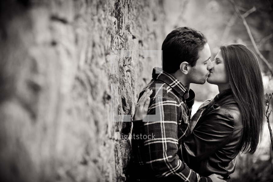 a couple kissing while leaning against a wall