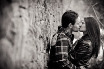 a couple kissing while leaning against a wall