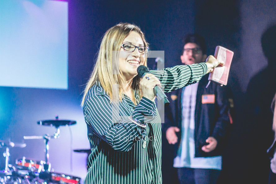 a woman holding a microphone and Bible 