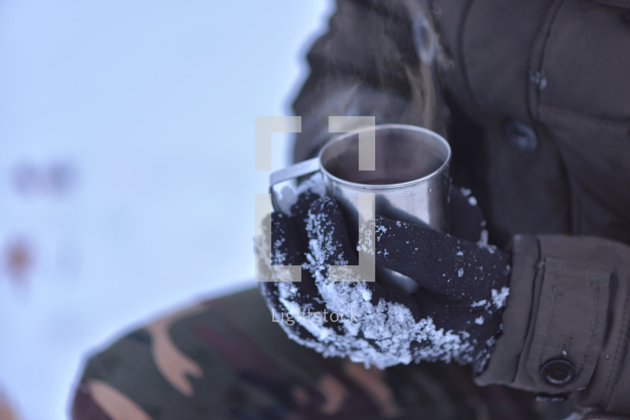 Side view of male hand in gloves holding cup with hot tea or coffee. Tea break. Winter time concept