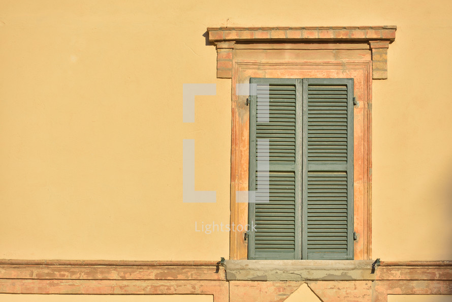 Closed green windows on yellow wall of old house in Florence city, Italy
