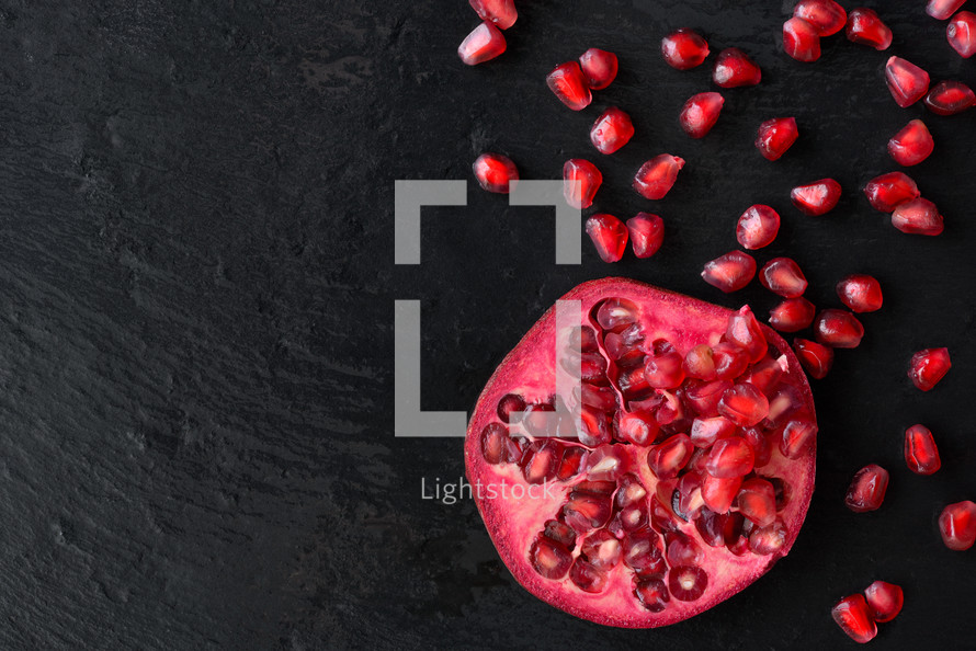 Fresh ripe pomegranate fruit on wet black stone vintage background
