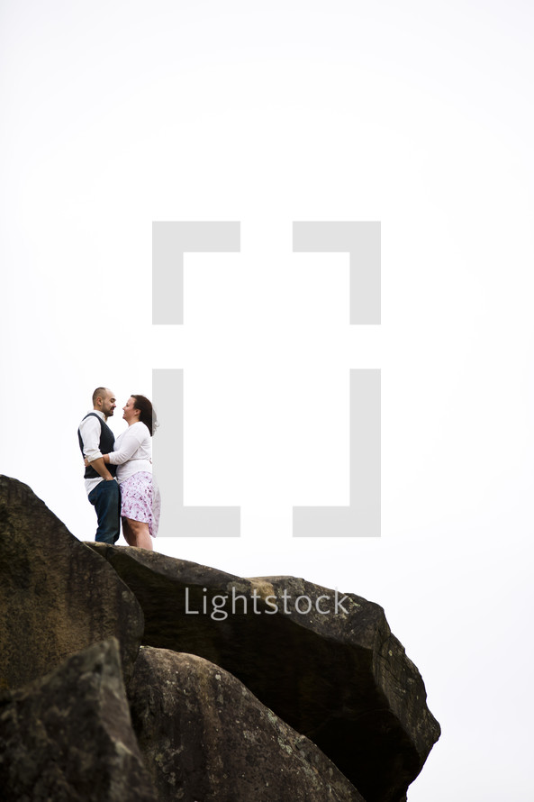 couple couple standing on top of a rock 