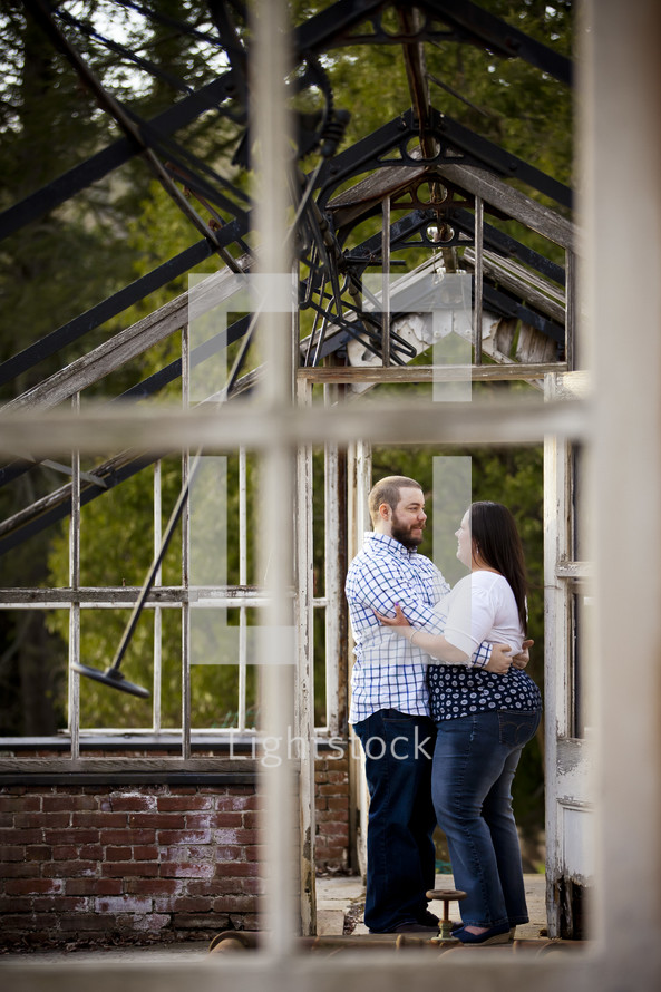 couple hugging outdoors in a shell of a house 