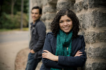 woman leaning against a wall with a man standing behind her