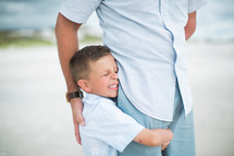 a son hugging his dad's leg