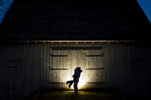 silhouette of a couple hugging in front of a barn 