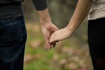 woman wearing an engagement ring holding hands with a man