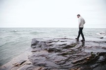 man walking on rocks near a shore 