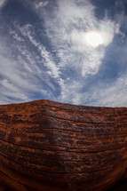 red rock cliff and clouds in a blue sky 
