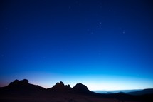 stars over mountain peaks in the night sky 