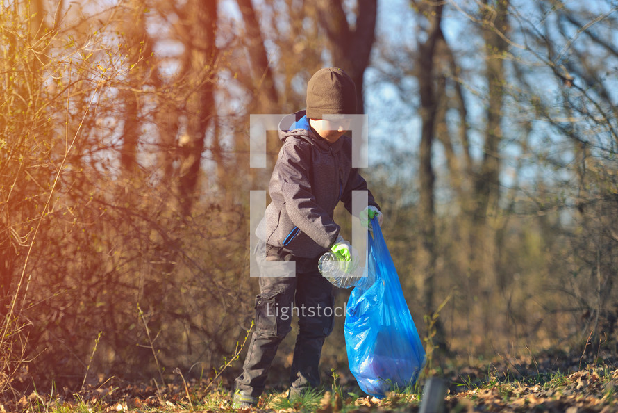A boy picks up a spring forest at sunset. Environment plastic pollution
