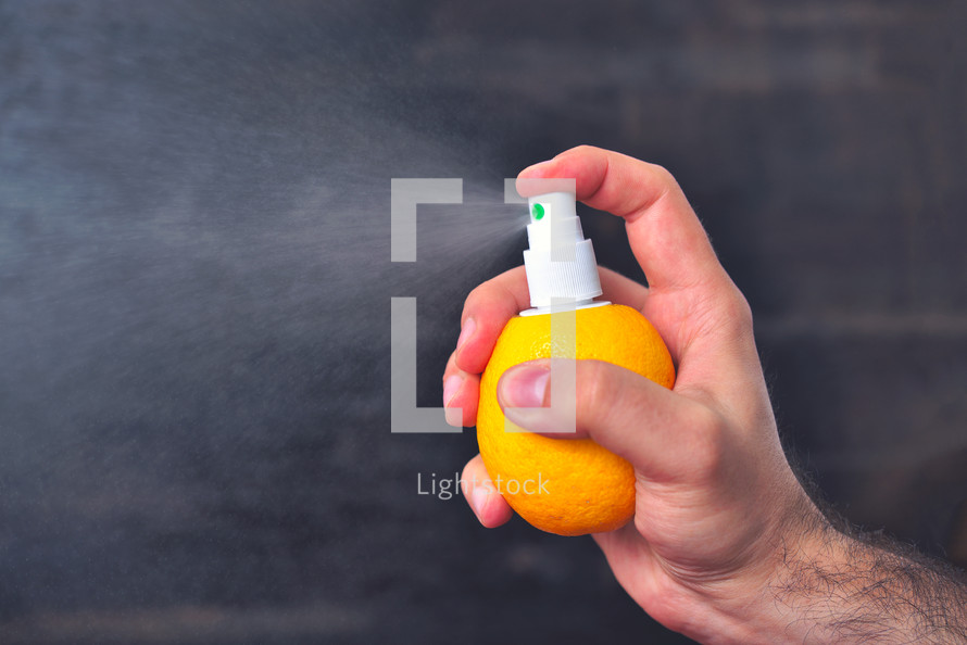 Man sprinkles juice from lemon with help of pump for spray.