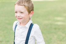a smiling boy child in suspenders 