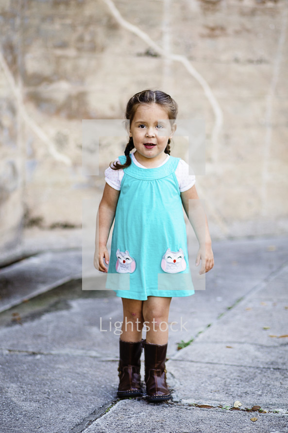 A young girl in a blue dress and boots.