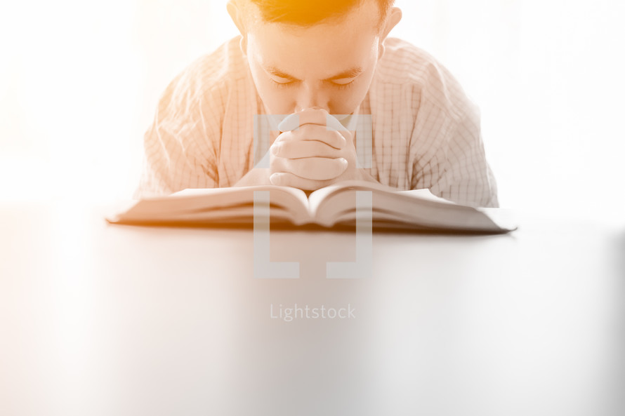 a man praying over an open Bible 
