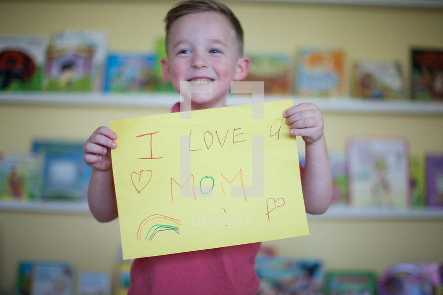a little boy holding a chalkboard sign that reads I love mom 