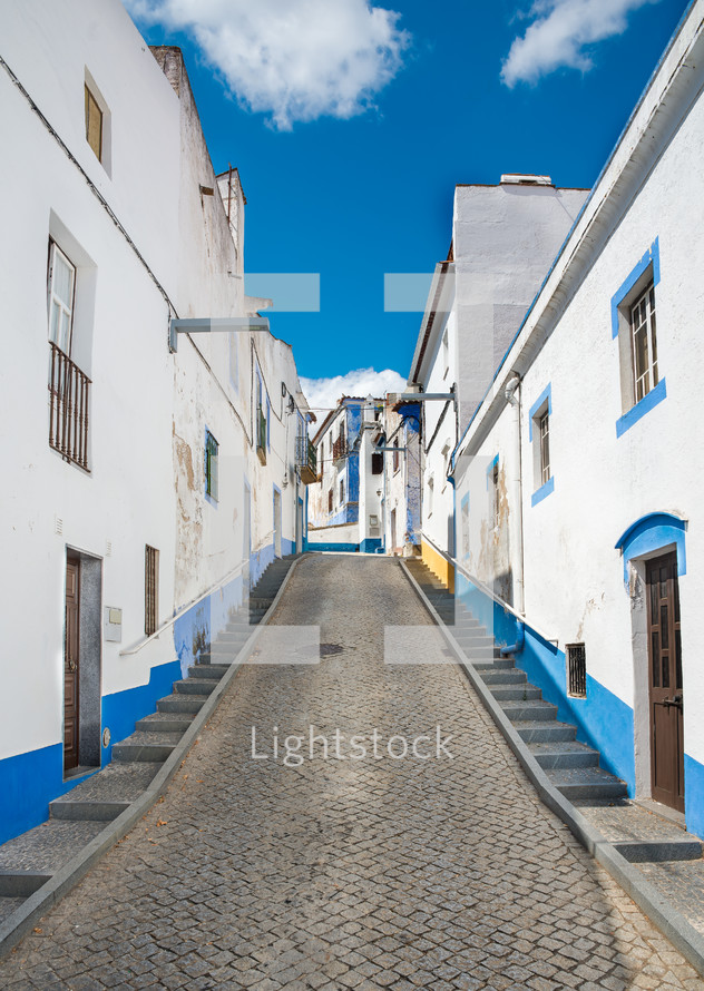 blue and white painted buildings along a cobblestone road 