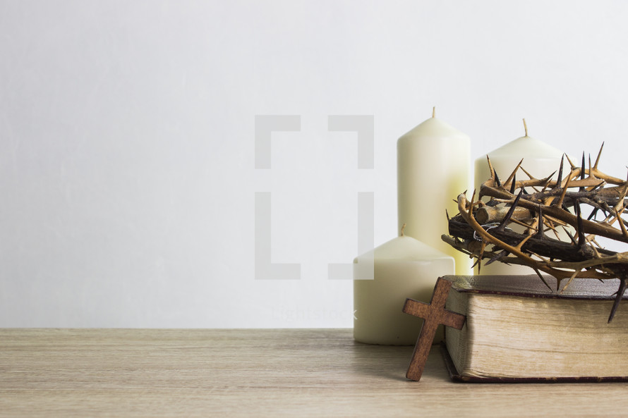 three white candles, a crown of thorns, and wood cross 