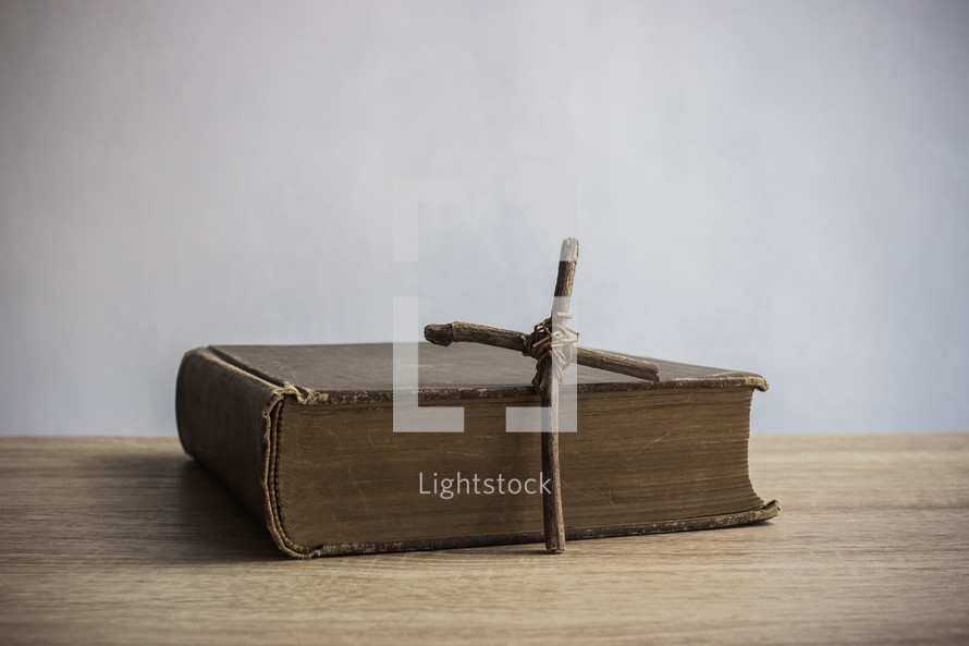 cross in front of the pages of a Bible 