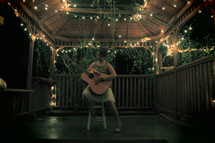 woman playing a guitar in a gazebo at night