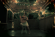 woman playing a guitar in a gazebo at night
