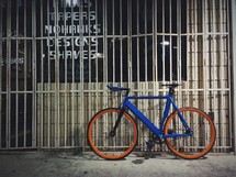 A bike resting in front of a gated store front. 